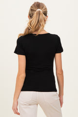 woman wearing a black maternity top viewed from the back, paired with light-colored pants