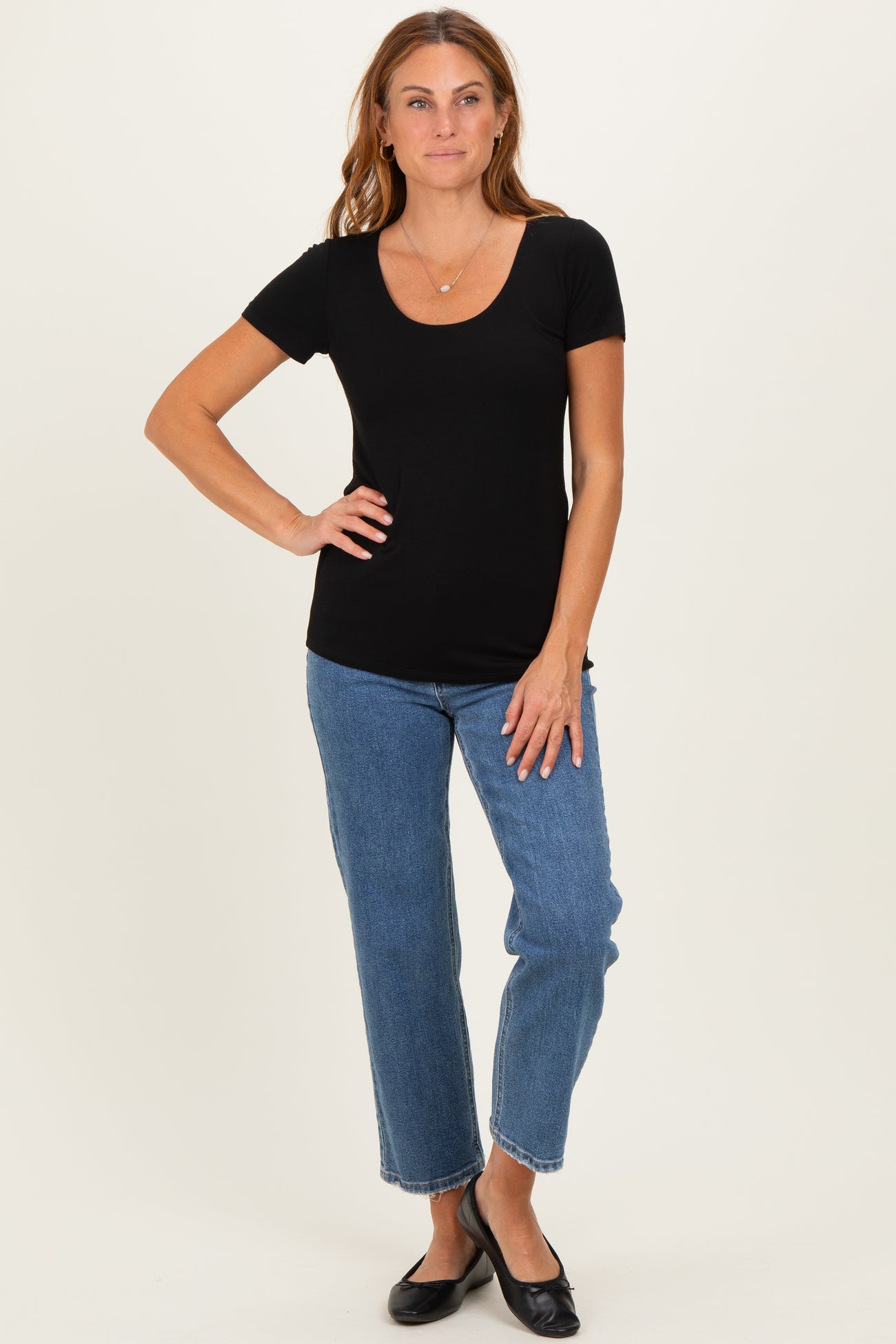woman wearing a black short sleeve scoop neck top and blue straight leg jeans
