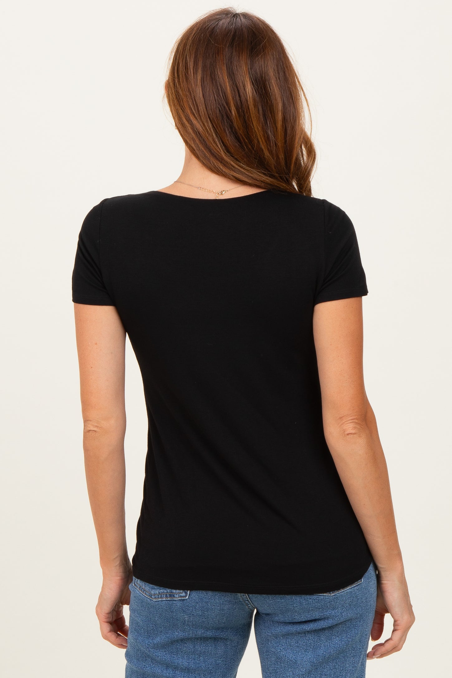 woman wearing a black short sleeve t-shirt, showing the back view with minimalistic design and fitted style