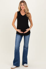 woman wearing a black sleeveless maternity top and holding her baby bump, paired with flared blue jeans