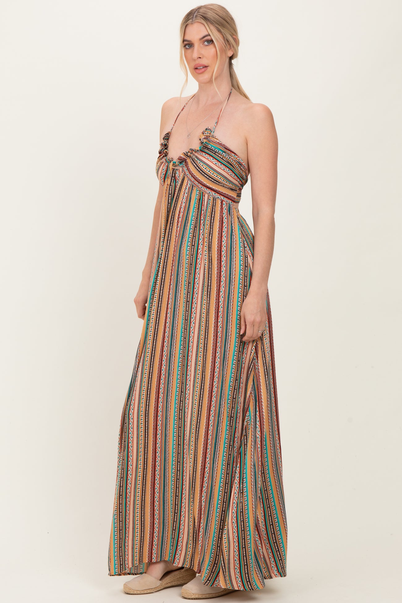 woman wearing a multicolored striped maxi dress with a knot detail at the bust and spaghetti straps