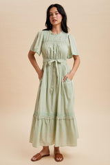 woman wearing a light green maxi dress with short puff sleeves, a cinched waist, and pockets