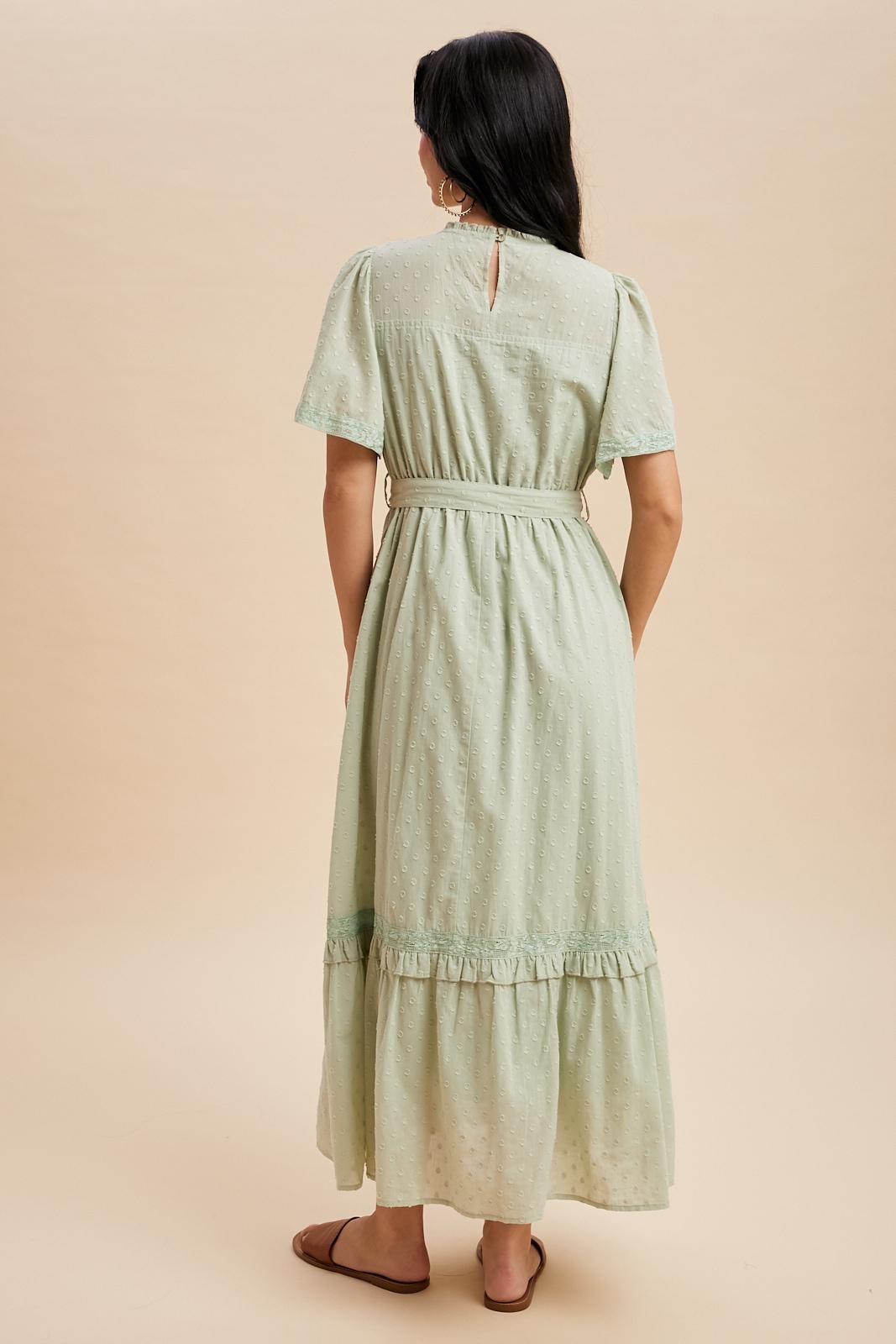 woman wearing a mint green maxi dress with short sleeves and a ruffled hem, shown from the back