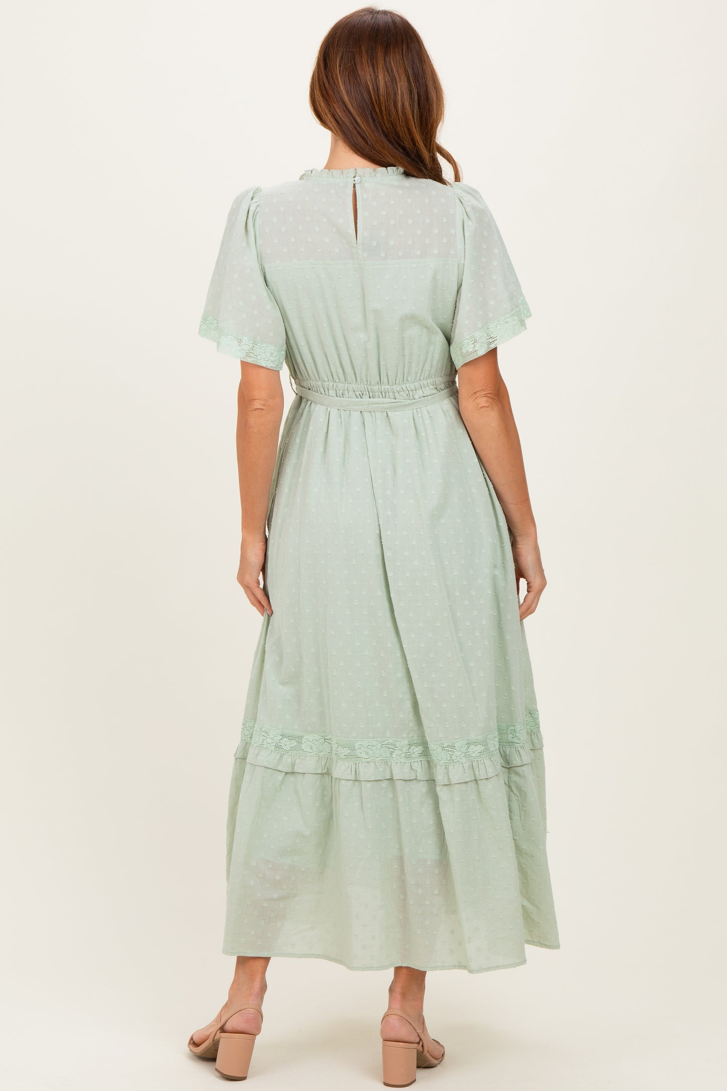 woman wearing a mint green polka dot maxi dress with short sleeves and a ruffled hem, shown from the back
