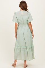 woman wearing a mint green polka dot maxi dress with short sleeves and a ruffled hem, shown from the back