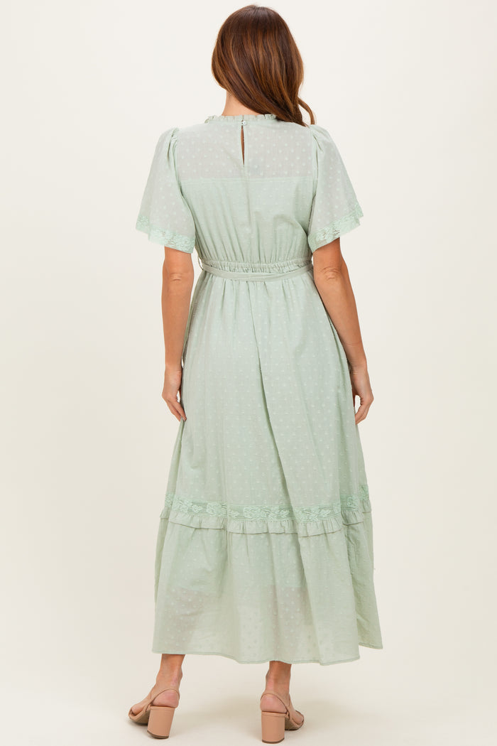 woman wearing a mint green polka dot maxi dress with short sleeves and a ruffled hem, shown from the back