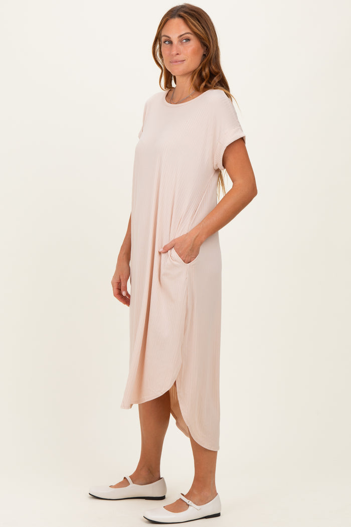 woman wearing a light pink short sleeve midi dress with pockets and a relaxed fit