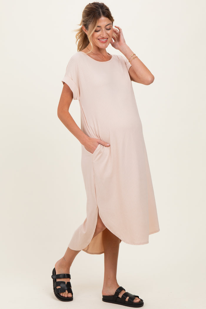 woman wearing a light pink maternity dress with short sleeves, side pockets, and a relaxed fit, showing her baby bump