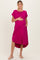 woman wearing a hot pink maternity dress with short sleeves and a high-low hem, holding her baby bump