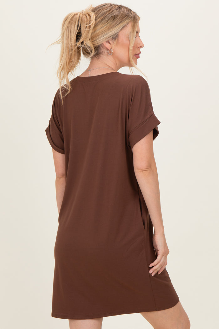 woman wearing a brown short sleeve t-shirt dress with rolled cuffs, standing with her back to the camera