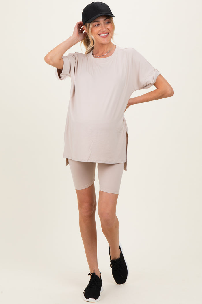 woman wearing a beige maternity activewear set featuring a long sleeve top and biker shorts, showing a baby bump