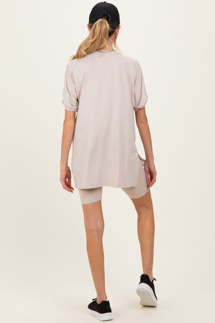 woman wearing a light beige maternity top and bike shorts, showing a relaxed fit and a casual look from the back