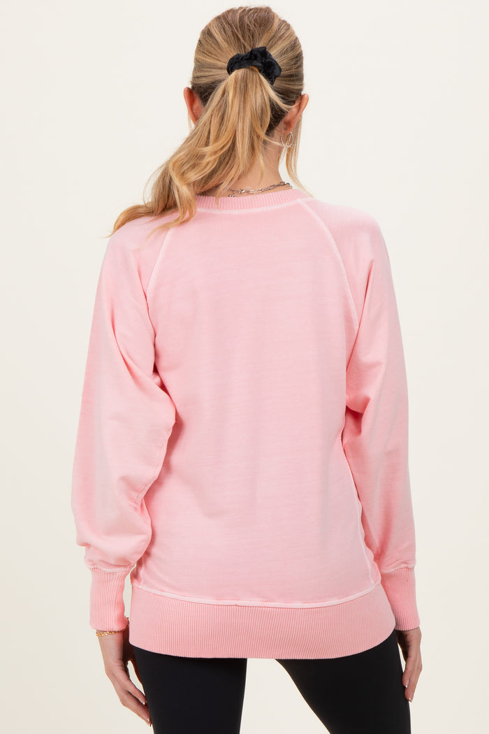 woman wearing a pink long sleeve maternity sweatshirt, seen from the back