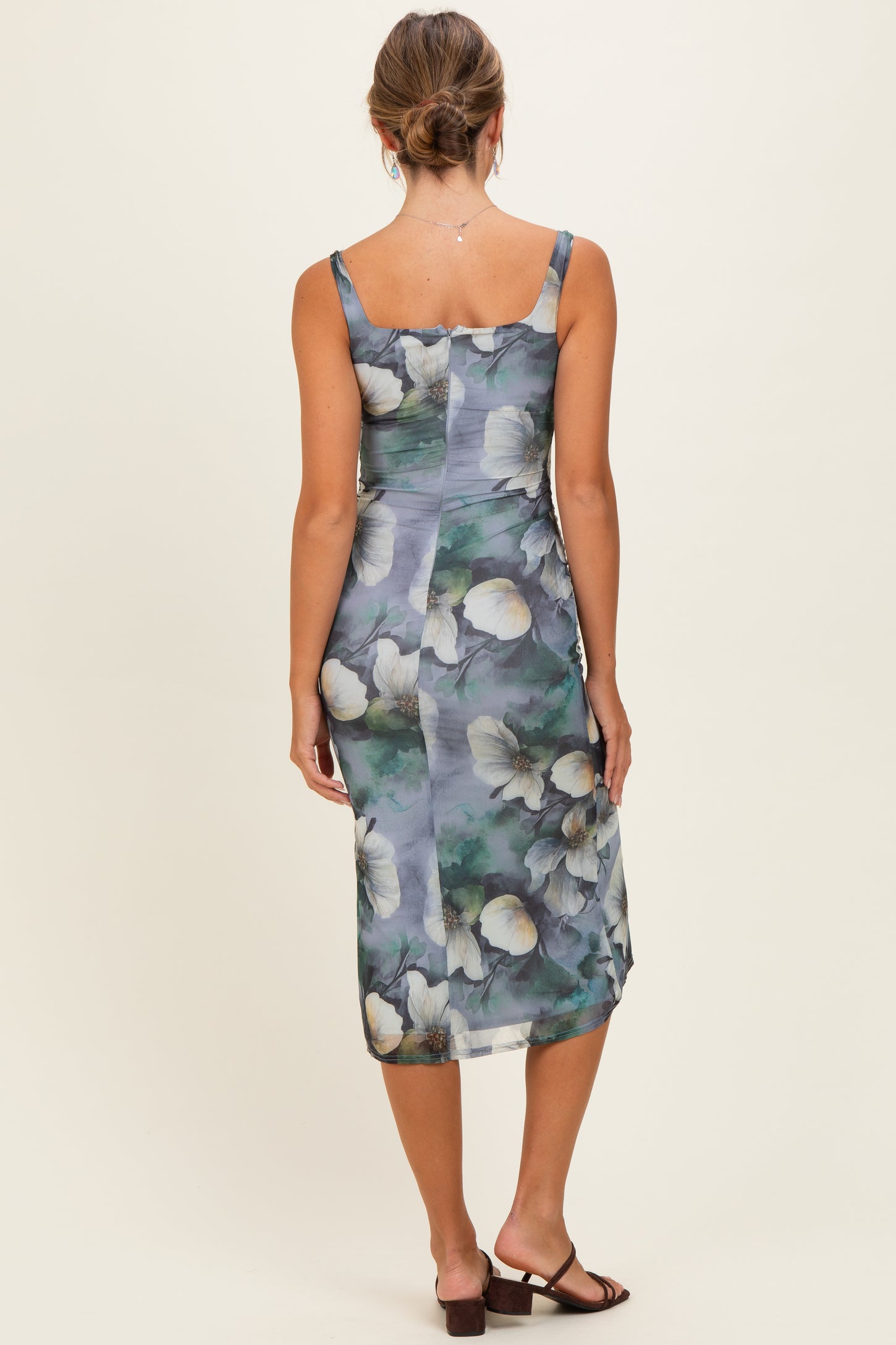 woman wearing a floral print midi dress with thin straps and a fitted silhouette, viewed from the back