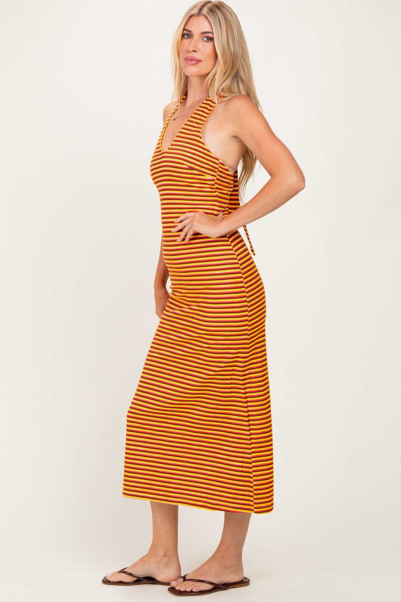 woman wearing a striped orange and brown halter neck midi dress with a fitted silhouette