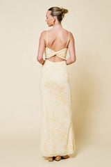 woman wearing a yellow floral backless maxi dress with thin straps, viewed from the back