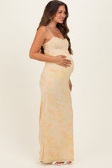 woman wearing a light yellow floral maternity dress, showcasing her baby bump