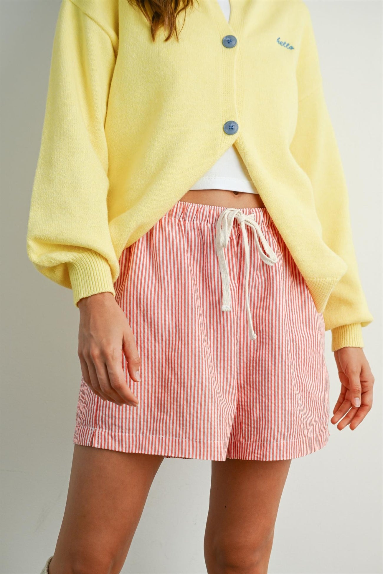 woman wearing a yellow cardigan and red and white striped shorts with an elastic waistband and drawstring