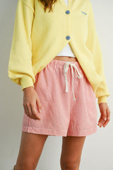 woman wearing a yellow cardigan and red and white striped shorts with an elastic waistband and drawstring