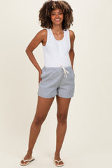 woman wearing a white maternity tank top and blue striped maternity shorts with pockets and drawstring detail