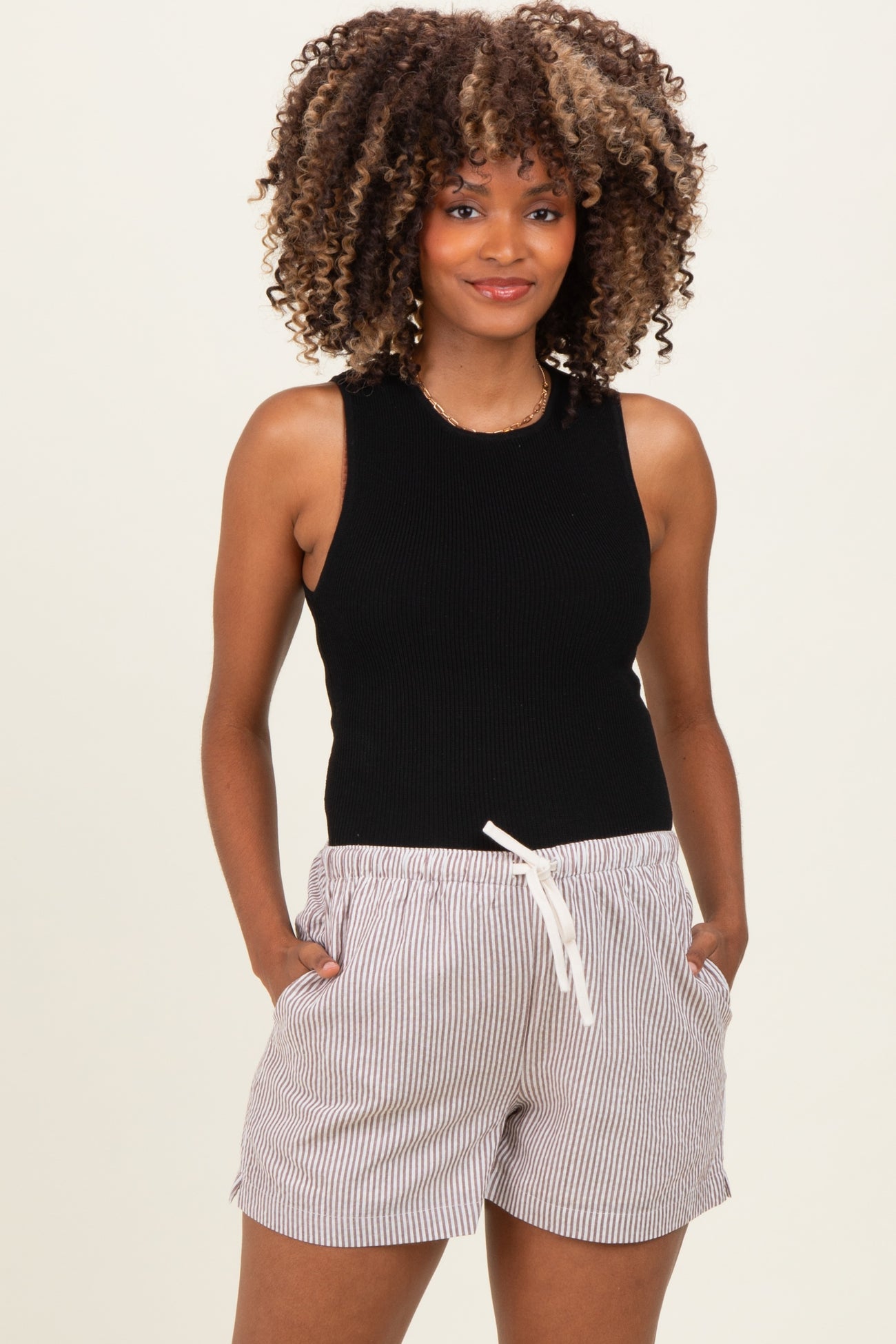 woman wearing a black sleeveless top and striped maternity shorts with an elastic waist and side pockets