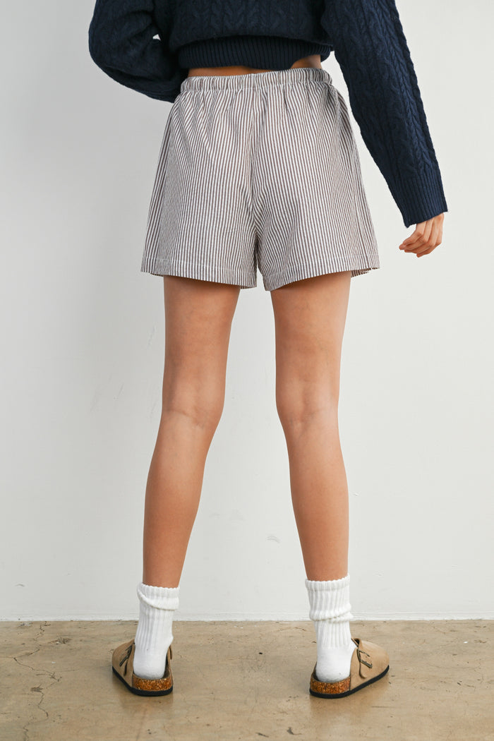 woman wearing striped shorts with an elastic waistband and casual shoes, viewed from the back