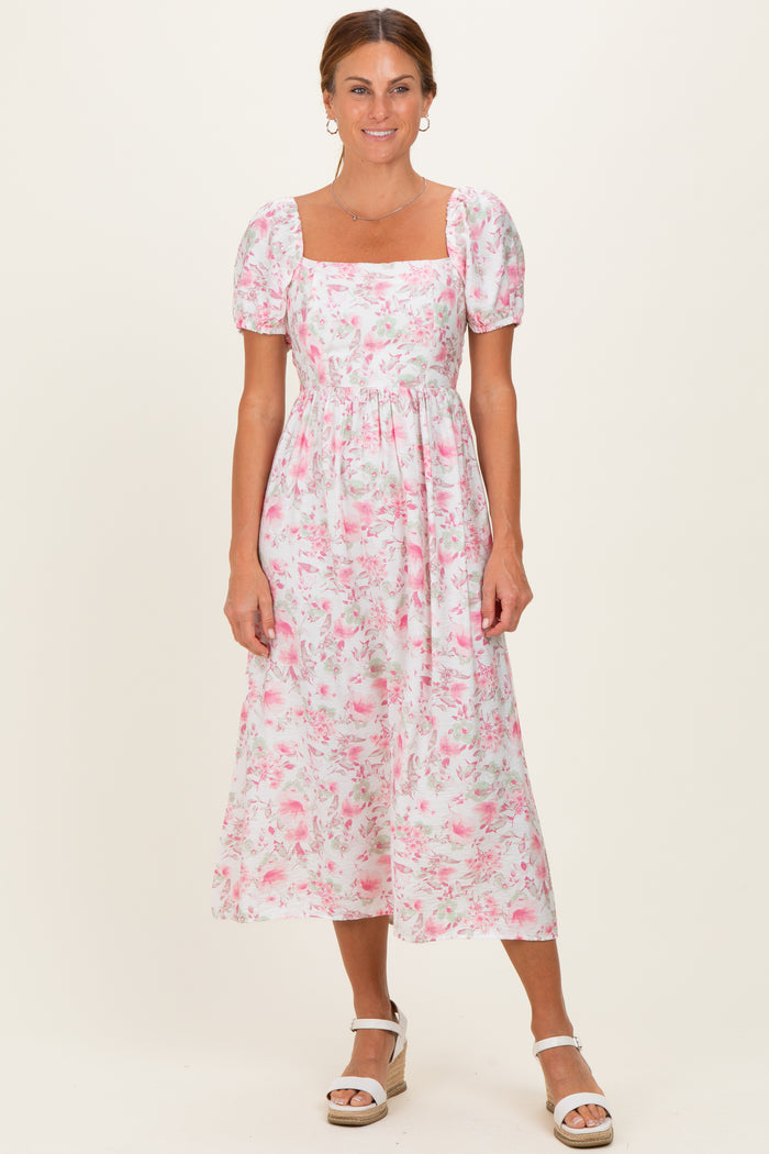 woman wearing a white floral midi dress with puff sleeves and a square neckline, standing against a neutral background