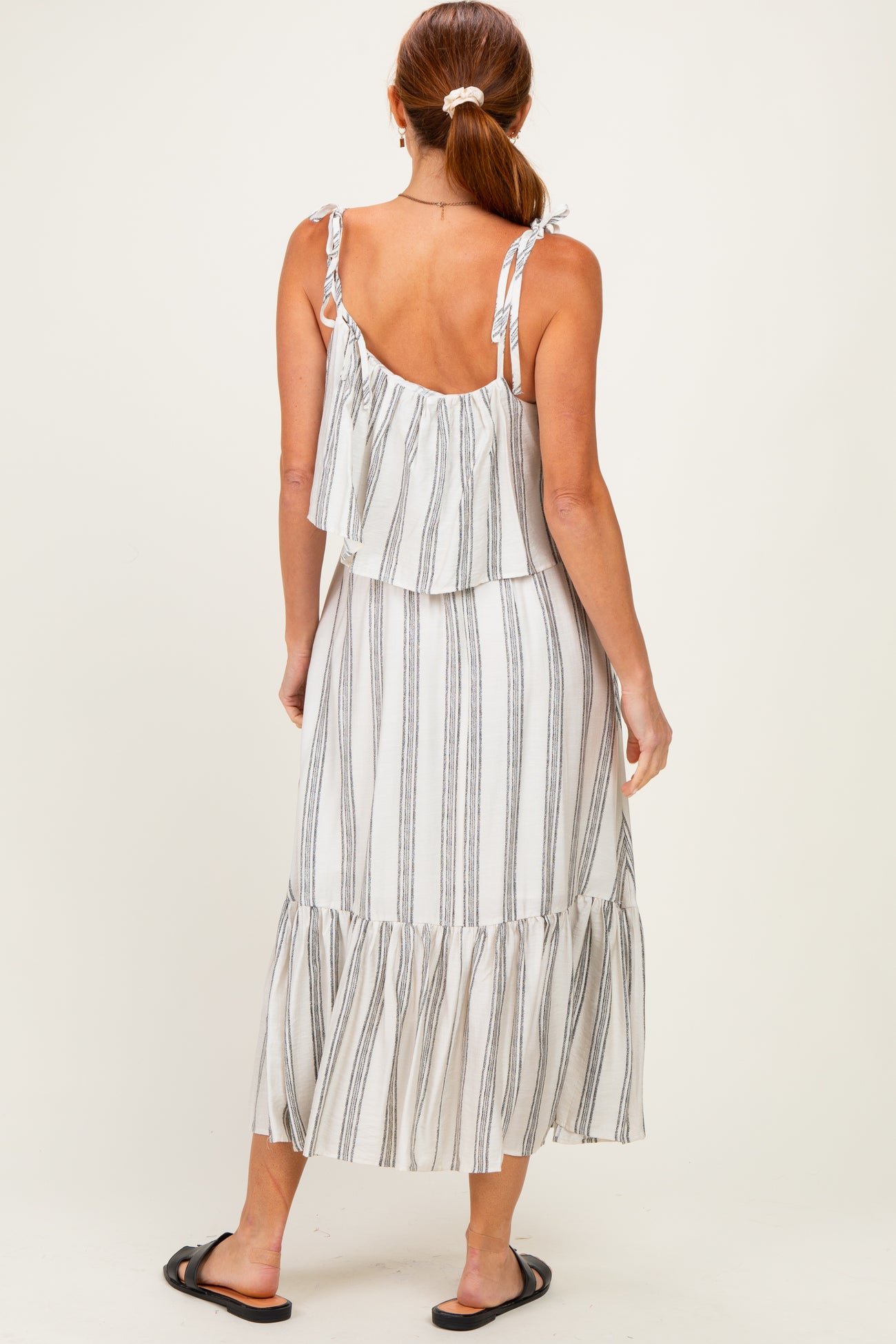 woman wearing a white and striped tiered maxi dress with ruffle straps and a flowy hemline