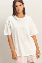 woman wearing a white oversized t-shirt with a chest pocket and smiling at the camera