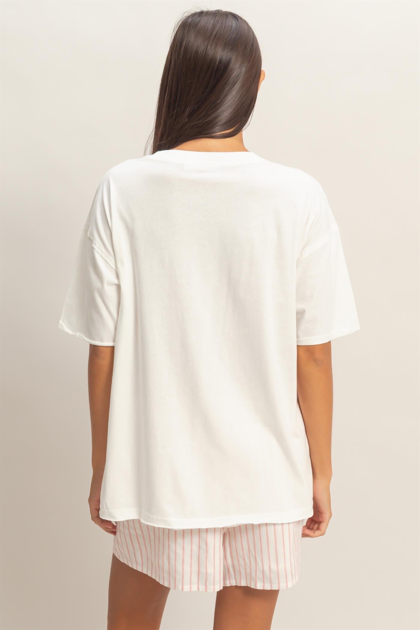 woman wearing a relaxed fit white oversized t-shirt and pink striped shorts, view from the back