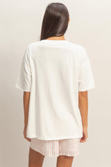 woman wearing a relaxed fit white oversized t-shirt and pink striped shorts, view from the back