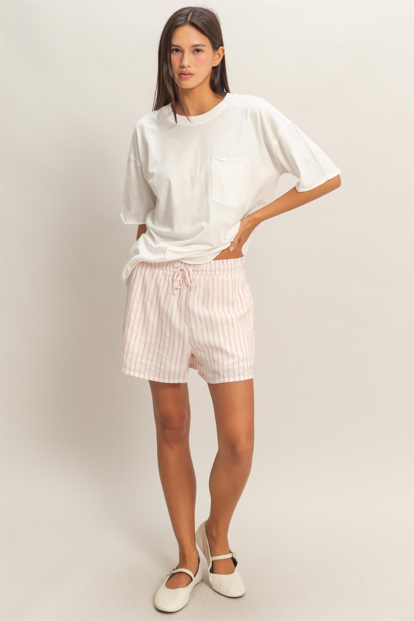 woman wearing a white oversized t-shirt with a pocket and pink striped shorts