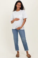 woman wearing a white maternity t-shirt and blue rolled-up jeans, gently holding her baby bump
