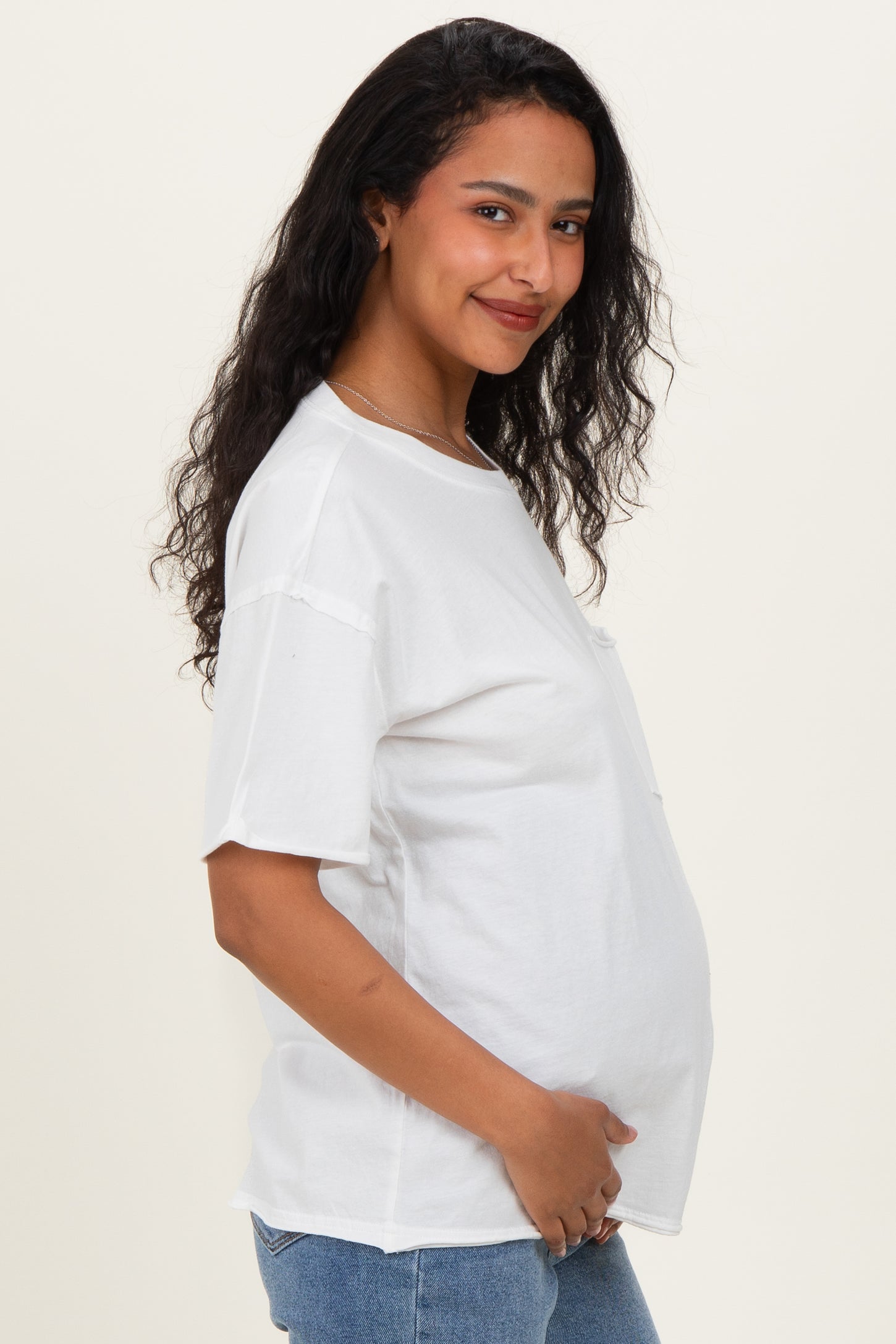 woman wearing a white oversized maternity t-shirt and holding her baby bump