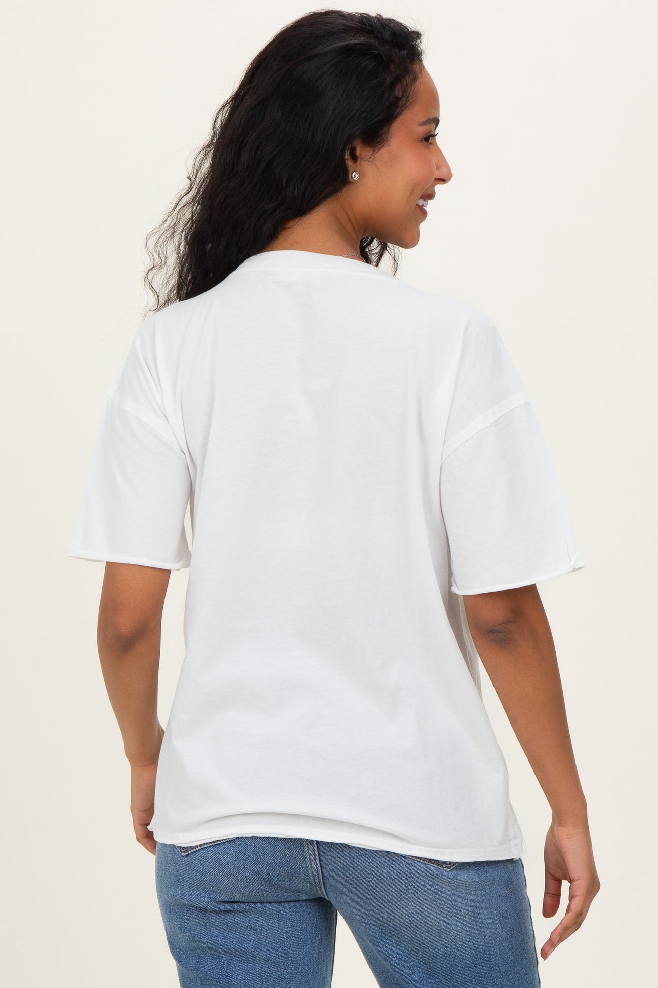 woman wearing a white oversized t-shirt with short sleeves, showing her back and paired with blue jeans, maternity wear
