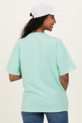 woman wearing a mint green oversized t-shirt and a white cap, showing a relaxed fit suitable for maternity wear