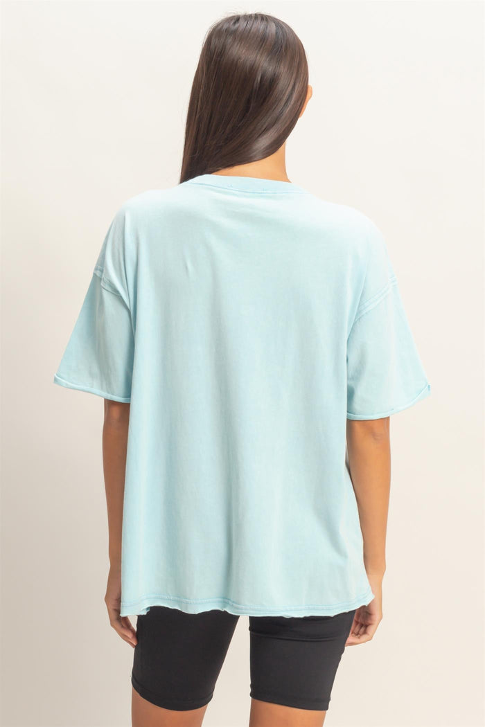 woman wearing a light blue oversized t-shirt with short sleeves and back view, paired with black bike shorts