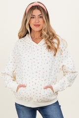 woman wearing a cream floral print maternity hoodie with a v-neck and front pockets