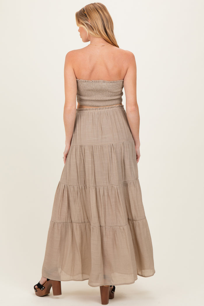 back view of a woman wearing a brown strapless maternity maxi dress with tiered ruffles