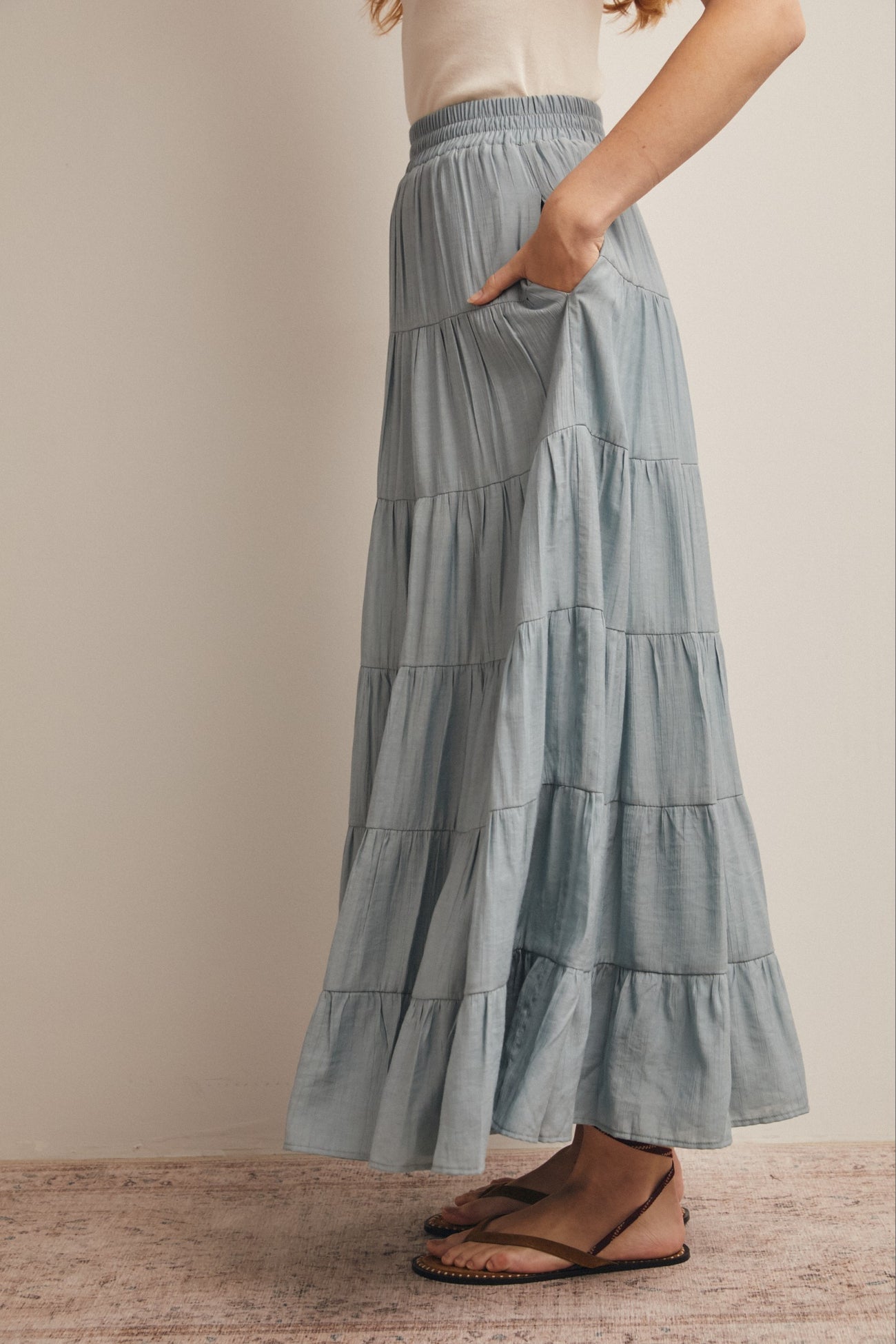 woman wearing a light blue tiered maxi skirt with pockets and a comfortable elastic waistband