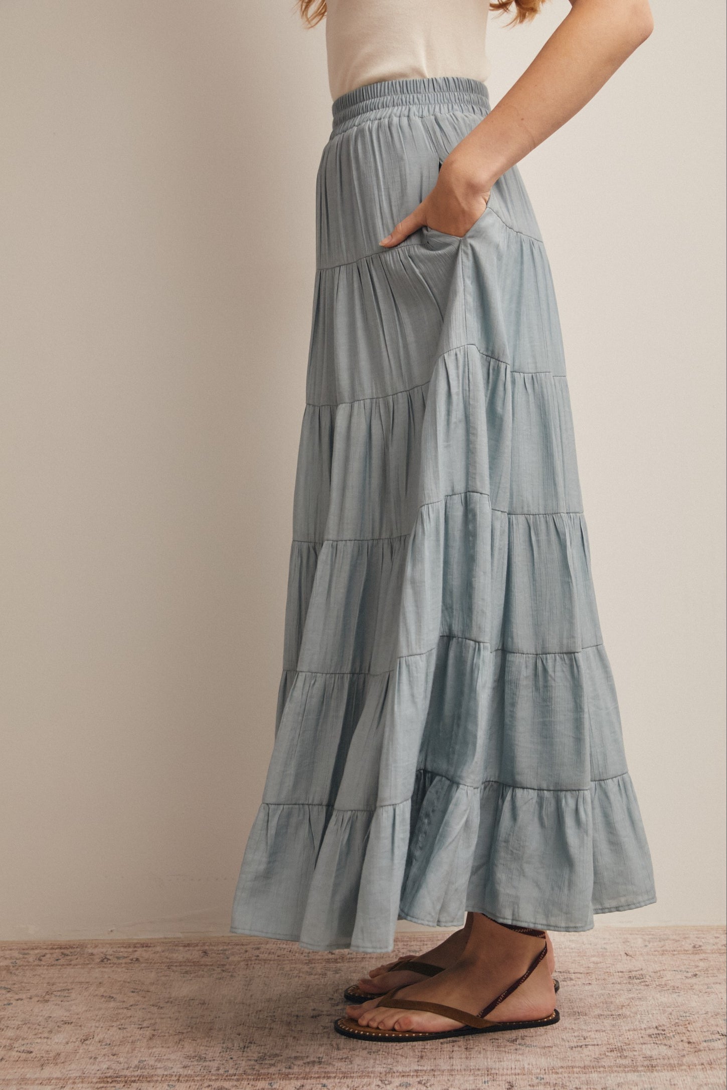woman wearing a light blue tiered maxi skirt with pockets and a comfortable elastic waistband