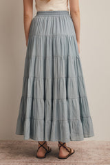 woman wearing a light blue tiered maxi skirt with an elastic waistband, seen from the back