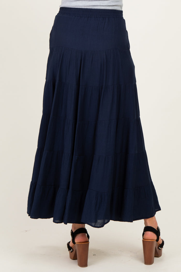 woman wearing a navy maternity maxi skirt with tiered ruffles, showing the back view and a relaxed fit