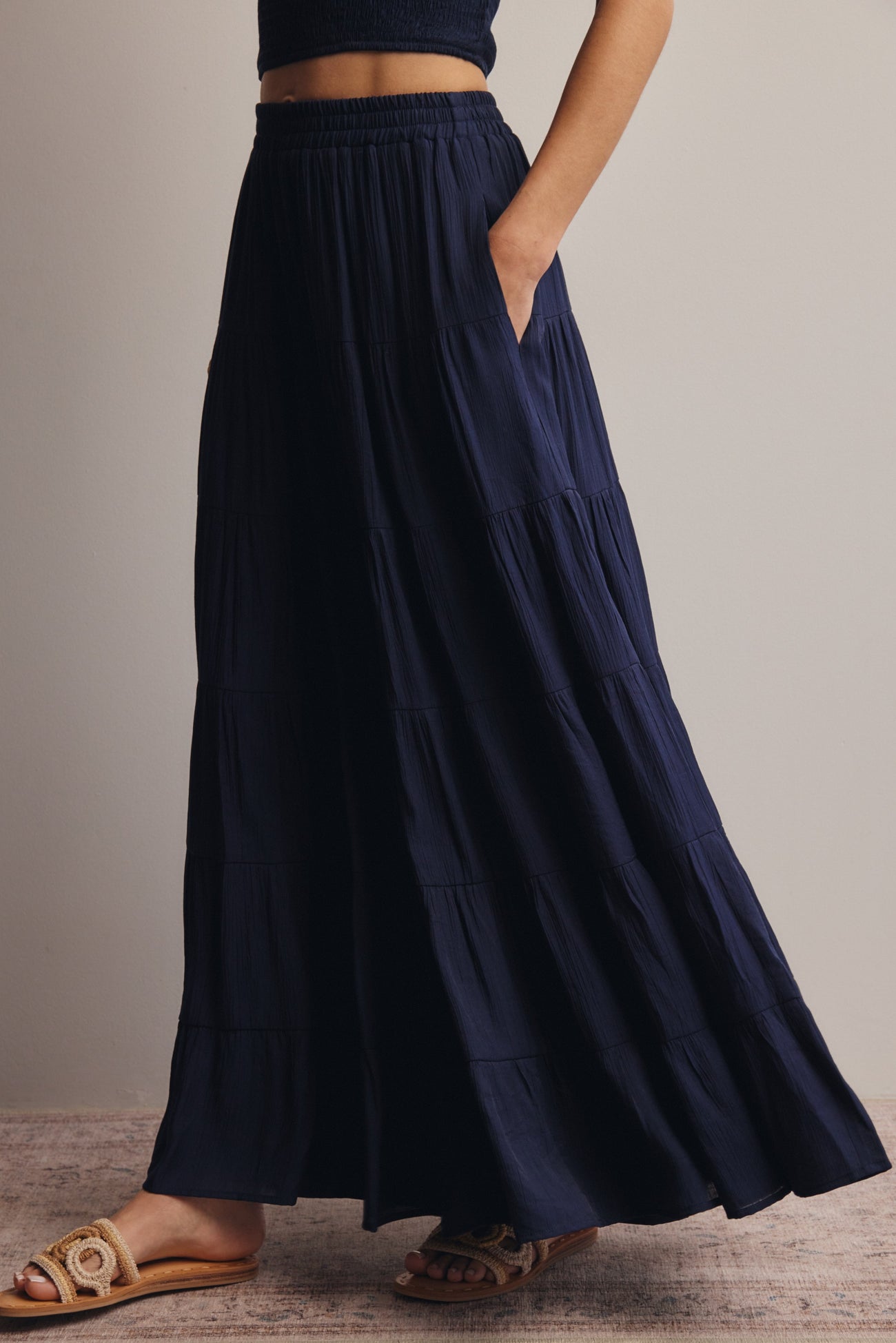 woman wearing a navy blue tiered maxi skirt with pockets and an elastic waistband