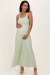 woman wearing a light green maternity dress with pleated detail and a visible baby bump
