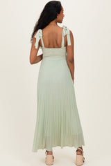 woman wearing a light green maternity maxi dress with tie straps and a fitted bodice, showing the back view