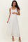 woman wearing a white pleated maternity dress and gently holding her baby bump