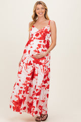 woman wearing a white maxi maternity dress with red floral print and holding her baby bump