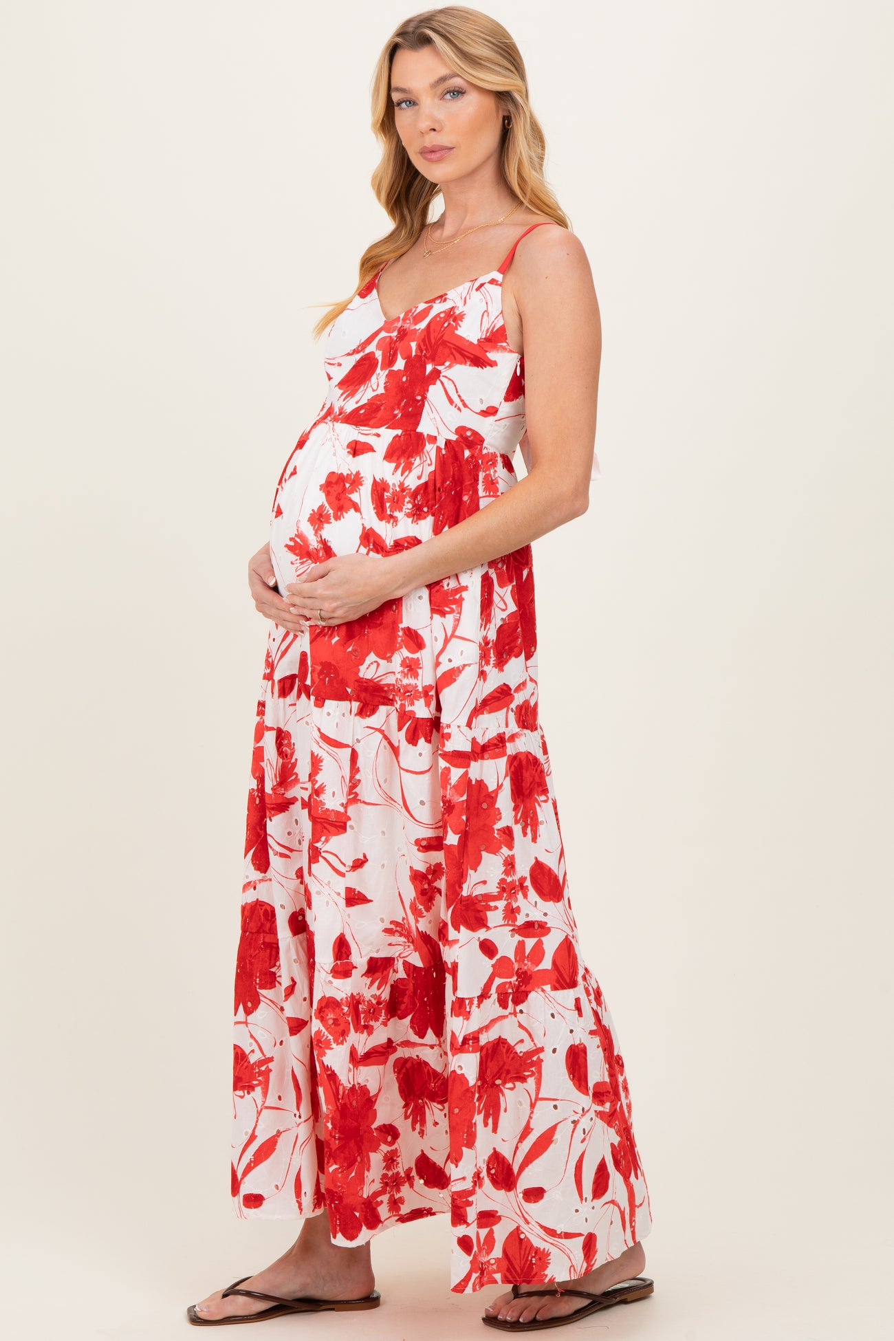 woman wearing a red and white floral maternity maxi dress with a baby bump, standing sideways
