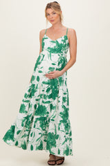 woman wearing a green floral print maternity maxi dress and holding her baby bump